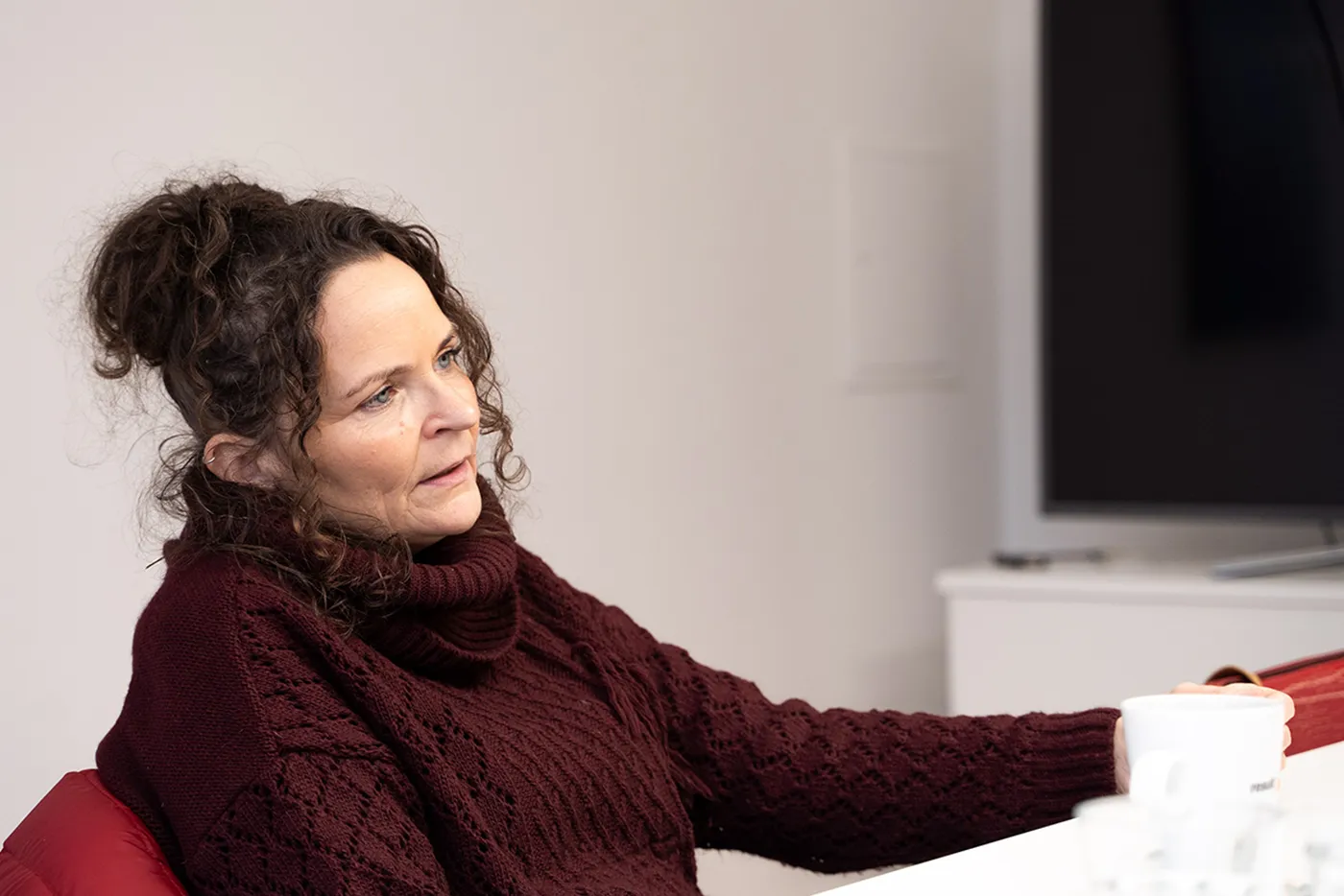 Melanie Krauss, stellvertretende Vorstandsvorsitzende des Vereins „Freunde der Kölner Straße und ihrer Bewohner e.V.“, sitzt mit einer Tasse in der Hand in einem Interview.