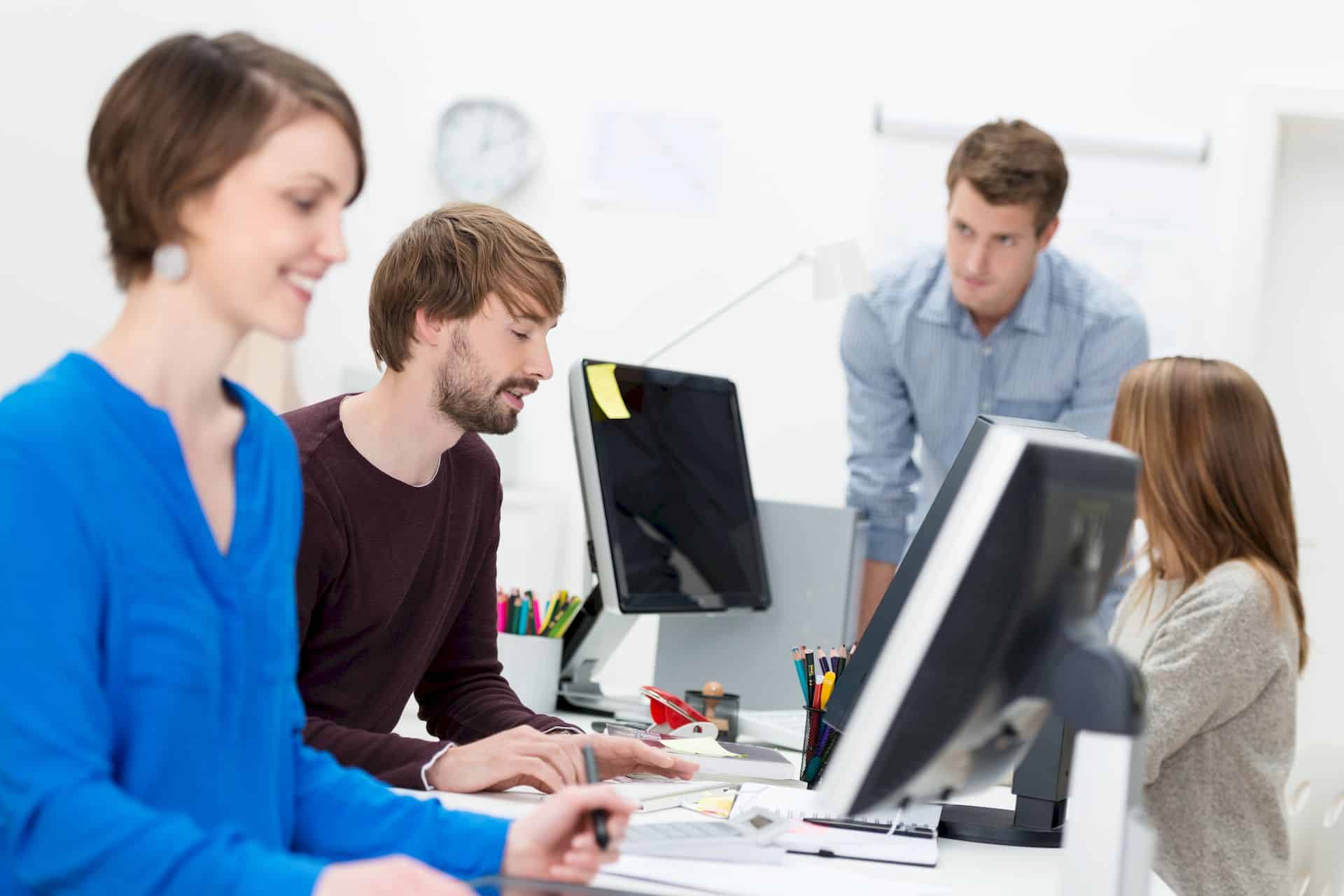 Vier Menschen arbeiten vor Monitoren in einer Redaktion.